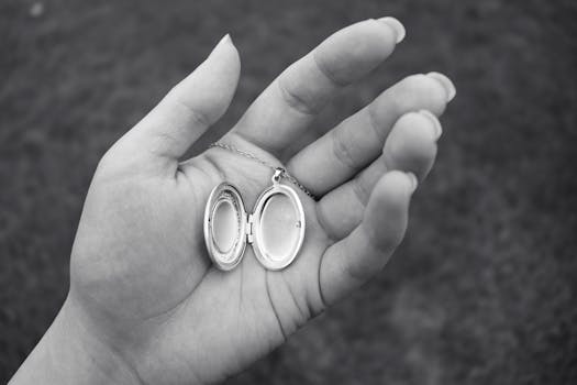 Close-up of a hand holding an open locket in a black and white image.