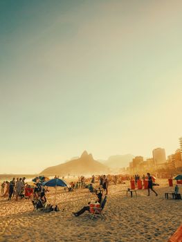 A vibrant scene on Ipanema Beach with people enjoying the sunny weather and scenic views in Rio de Janeiro, Brazil.
