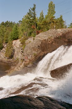 Stunning waterfall cascading over rocks with lush greenery surrounding it.