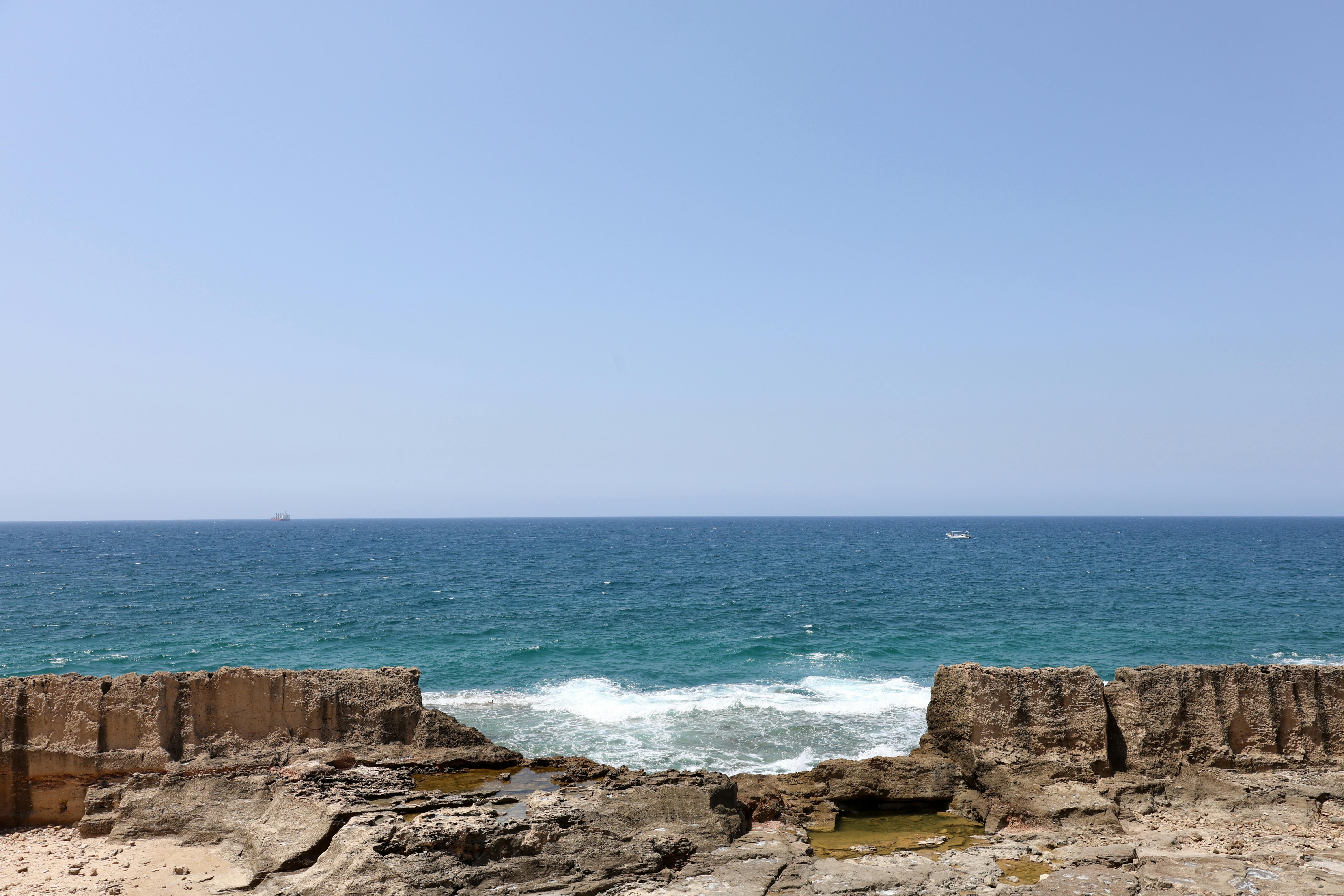 Peaceful Mediterranean coastline in Batroun, Lebanon, with rocky cliffs and blue sea.