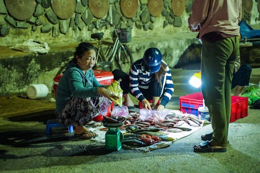 Two women selling fresh fish at a night market. Street vendor setup with fresh catch displayed.