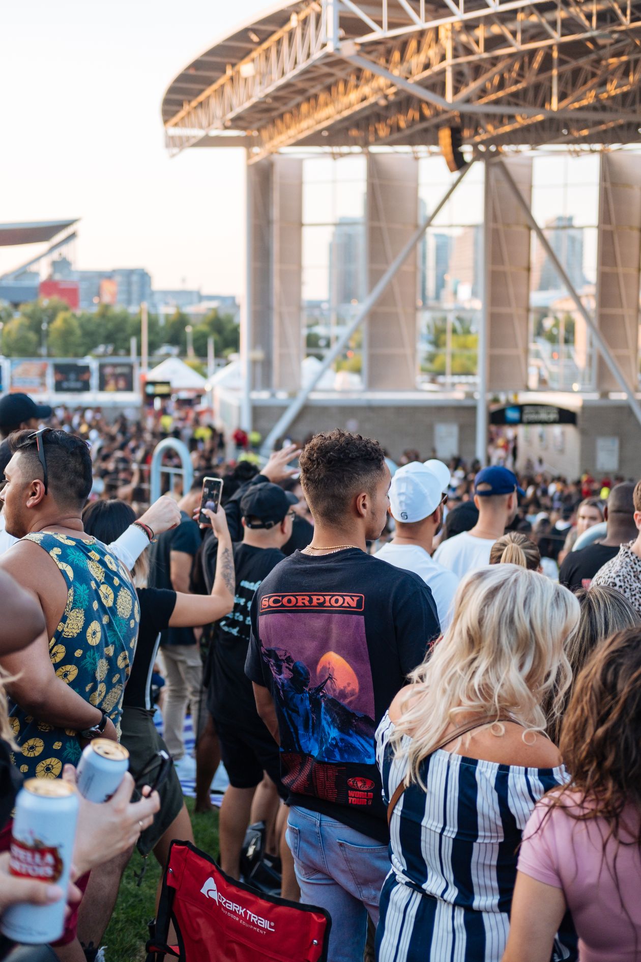 Vibrant crowd enjoying a live outdoor summer concert in a park setting with stage and festive atmosphere