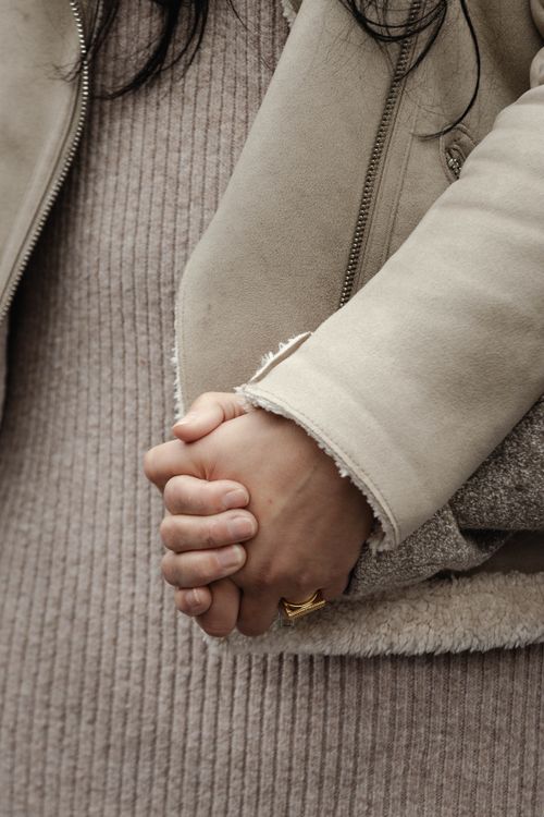 Free Detailed image of two women holding hands, showcasing intimacy and warmth through textured jackets and soft lighting. Stock Photo