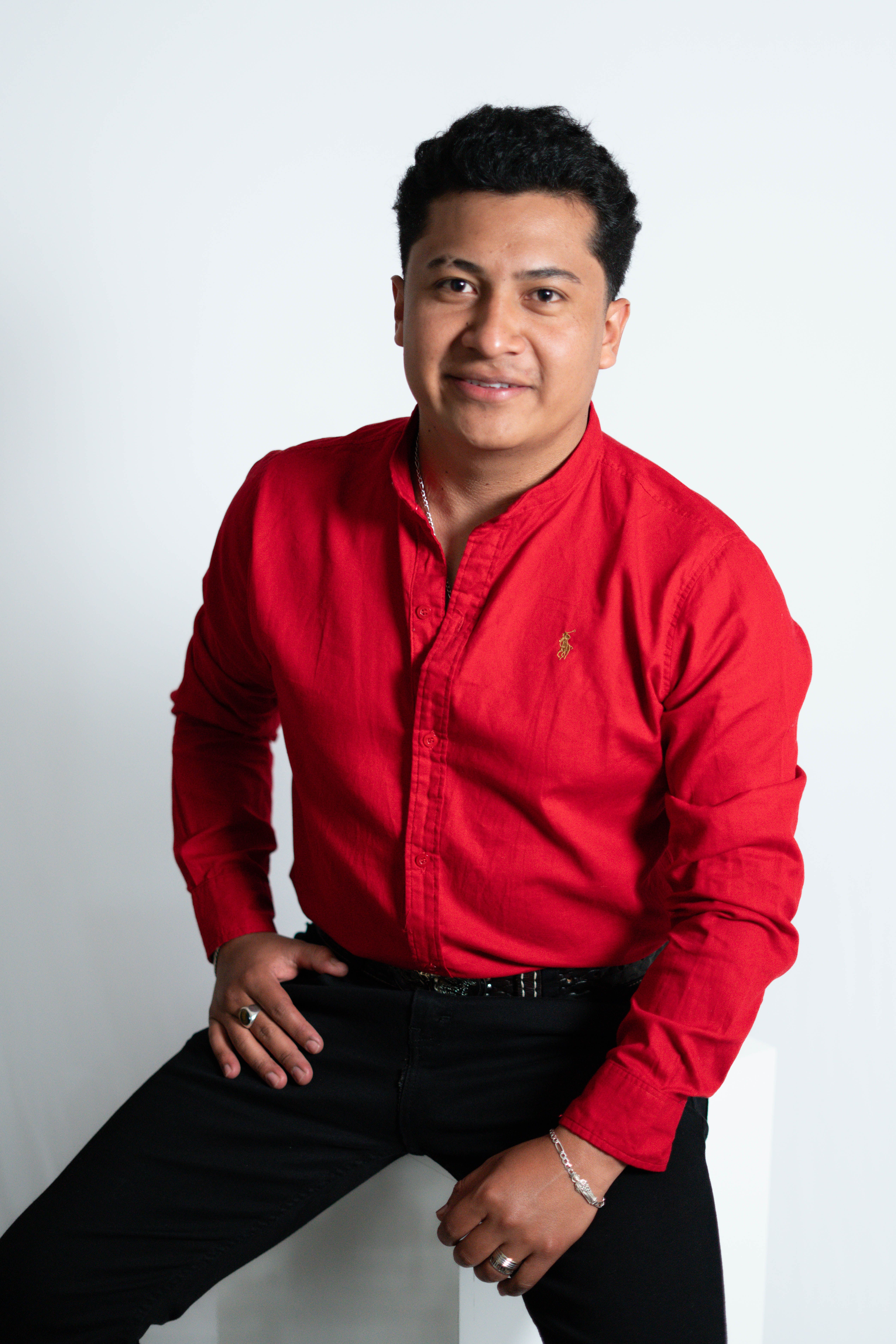 Studio portrait of a smiling man in a red shirt, ideal for business or lifestyle use.