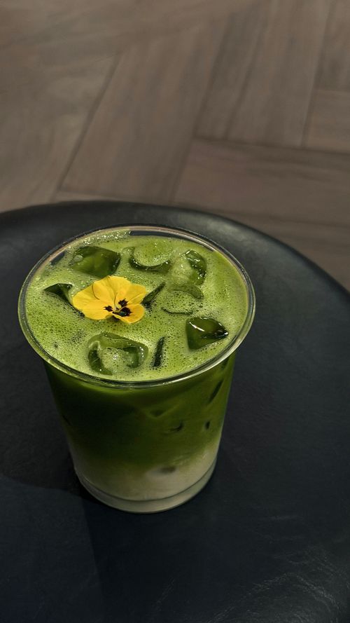 Free A refreshing iced matcha latte topped with an edible flower on a dark table, captured in Ho Chi Minh City. Stock Photo