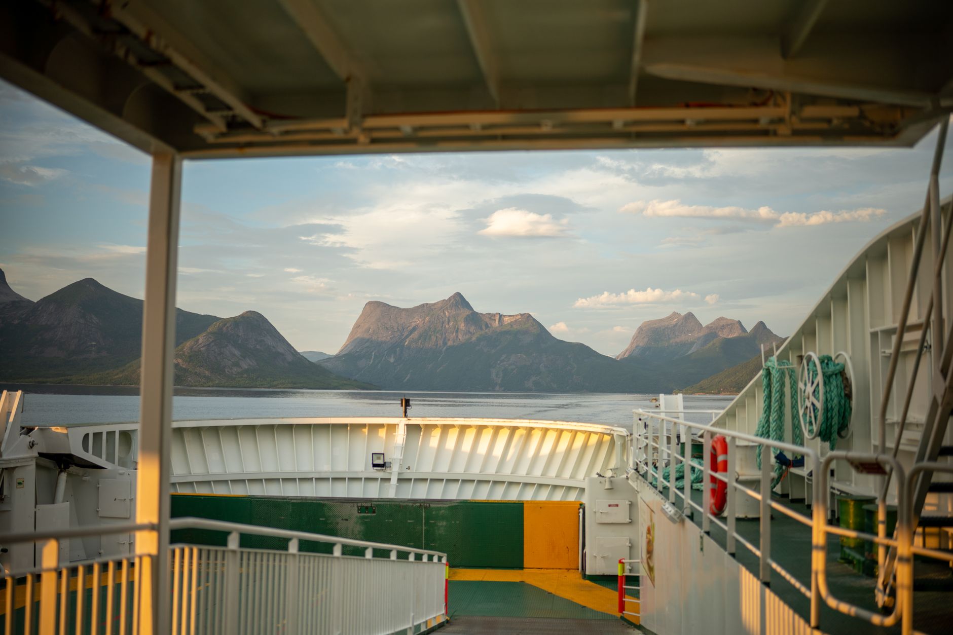 Experience the breathtaking view of Norwegian fjords from a ferry deck during a sunny day.