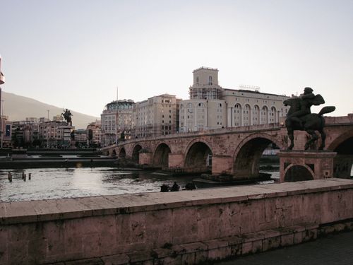 Free View of the Stone Bridge and waterfront in Skopje, North Macedonia, captured at twilight with historic statues and buildings. Stock Photo