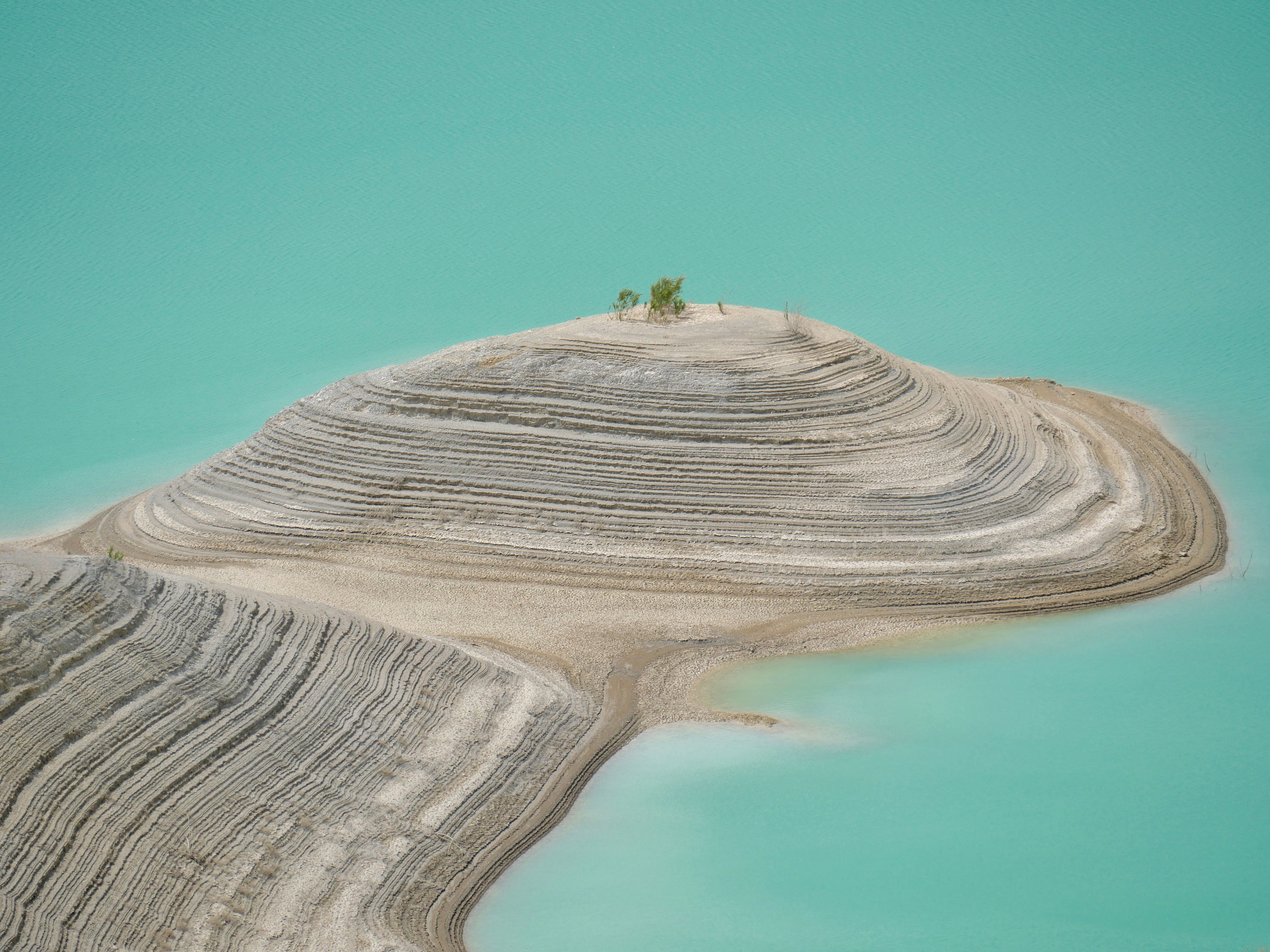 Aerial view of a unique striated island surrounded by turquoise waters. Nature's art.