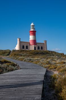 Cape Agulhas Lighthouse with red and white stripes on a clear day, visible path leading to entrance.