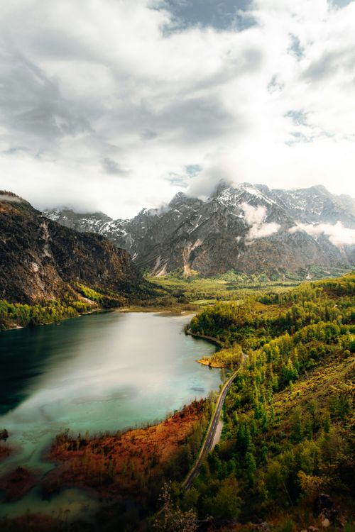 Free A breathtaking view of a serene alpine lake surrounded by lush greenery and towering mountains in Austria. Stock Photo