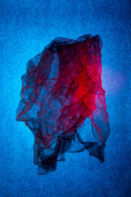 Free Colorful sheer fabric swirling against a vivid blue backdrop, creating a dynamic abstract composition. Stock Photo