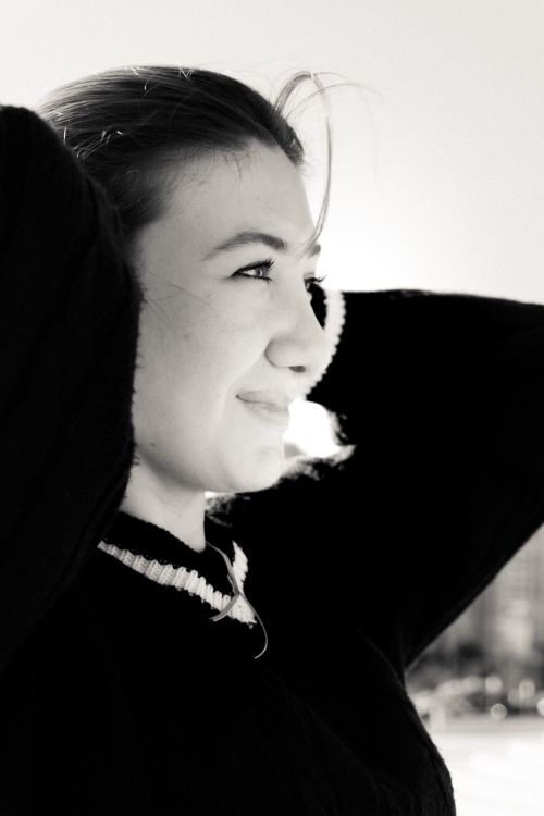 Free Profile of a smiling young woman enjoying a sunny day outdoors in black and white. Stock Photo