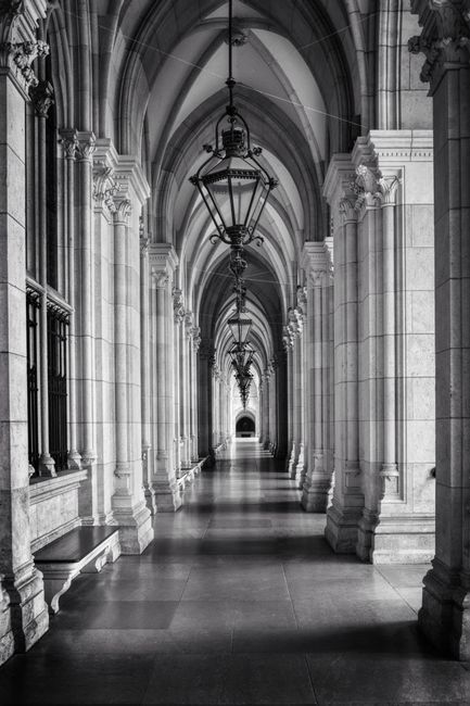 Stunning black and white capture of a gothic architectural corridor with elegant arches and symmetrical design.