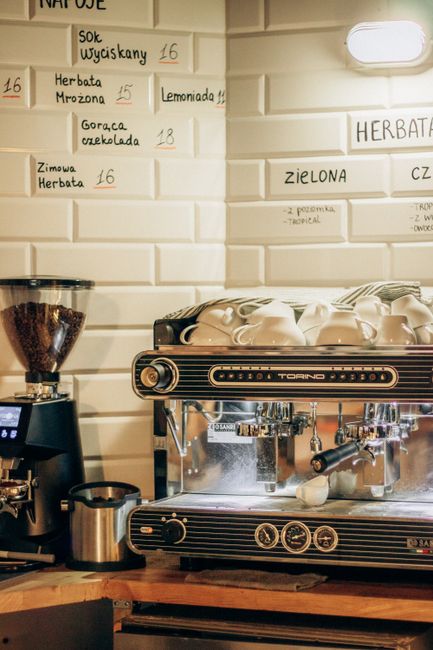 Close-up of a coffee shop counter with an espresso machine and wall menu.