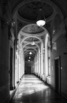 Arch-lined hallway with intricate ceilings in classic monochrome style.
