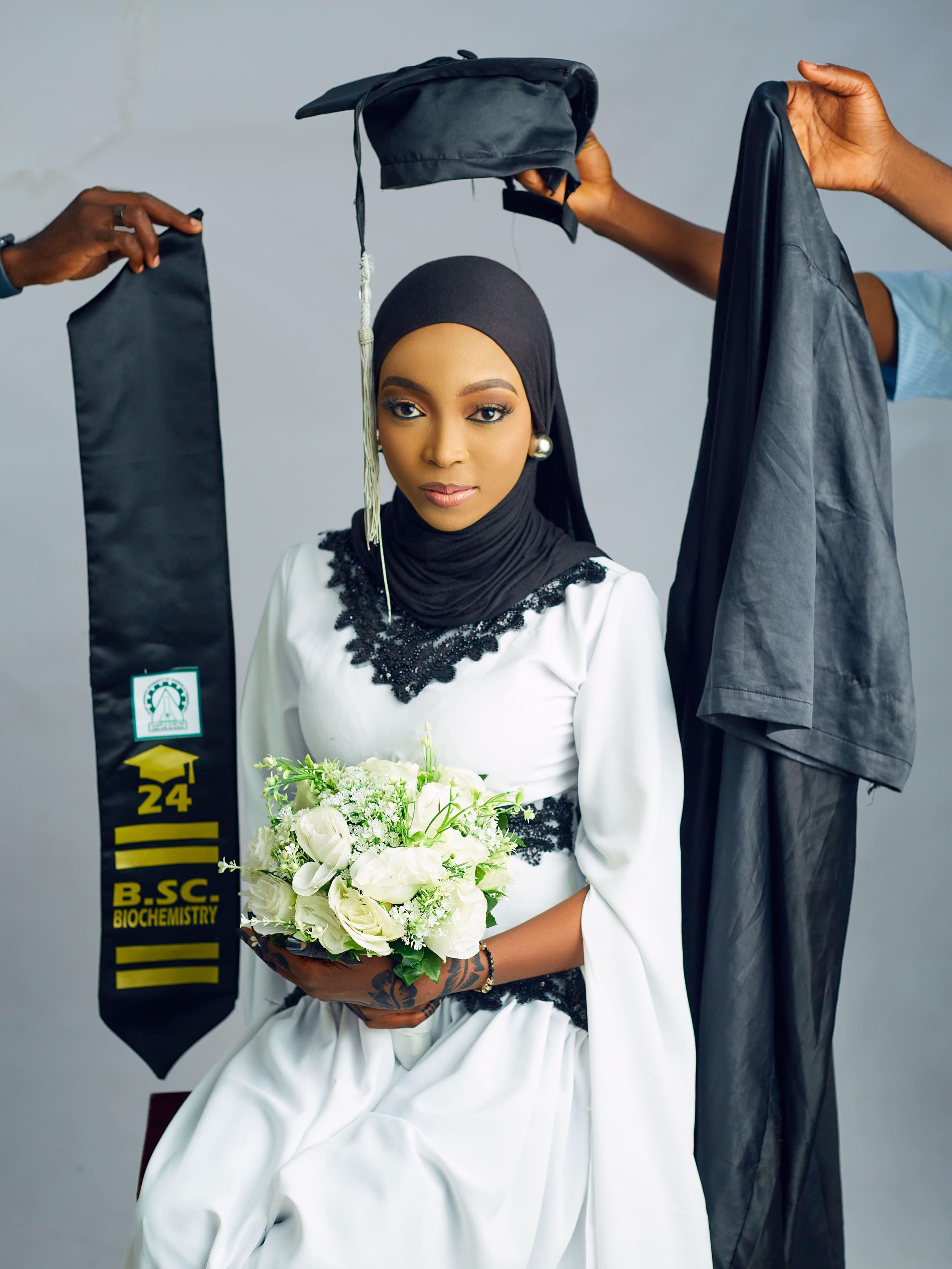 Nigerian woman in graduation gown holding bouquet, celebrating B.Sc in Biochemistry.