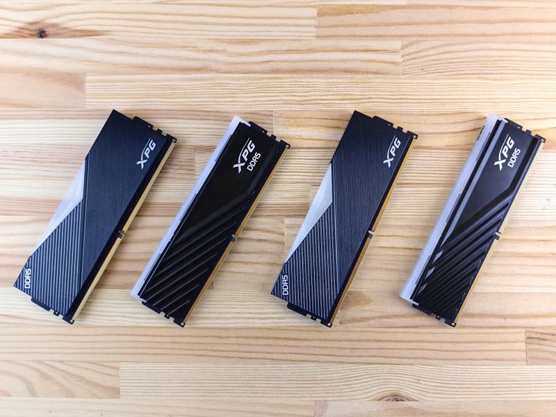 Four XPG DDR5 memory modules with black heat spreaders on a wooden surface