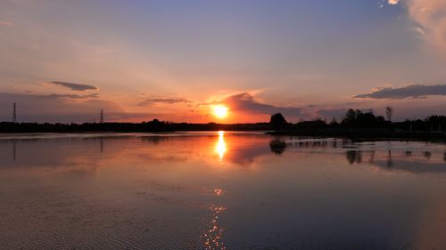 Free Beautiful sunset reflecting on a calm lake surrounded by nature, creating a serene atmosphere. Stock Photo
