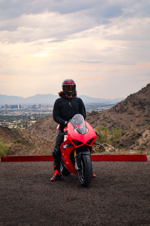 Free Rider in black helmet on red motorcycle with city skyline in background. Stock Photo