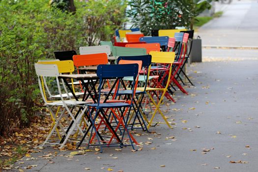 Vibrant chairs arranged along a sidewalk in autumn, Wien.
