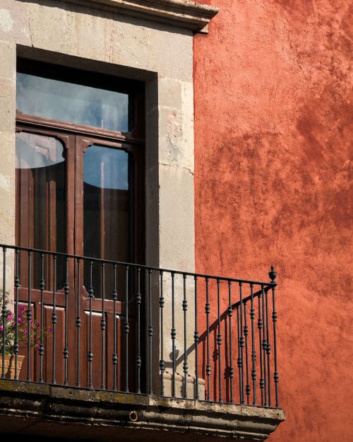 Free A charming balcony with iron bars against a vibrant red wall in Santiago de Querétaro, Mexico. Stock Photo