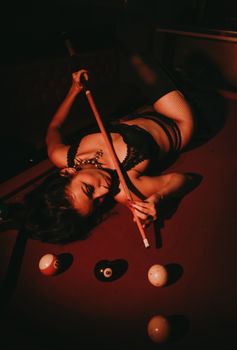 Dramatic, moody shot of a woman playing pool, focusing intensely. Perfect for nightlife themes.