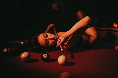 Free Moody image of a woman on a pool table, bathed in warm light, creating a dramatic atmosphere. Stock Photo