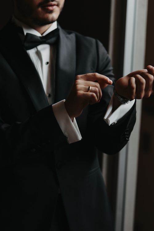 Free A man in a black tuxedo adjusting his cufflinks, highlighting elegance and style. Stock Photo