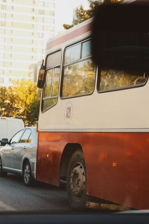 Free Side view of a bus and cars in city traffic during daytime. Stock Photo