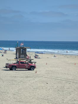 Lifeguard patrol truck parked near a lifeguard tower on Newport Beach, California.