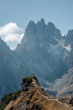 Explore the stunning mountain path in the Dolomites, Italy with breathtaking peaks and clear skies.