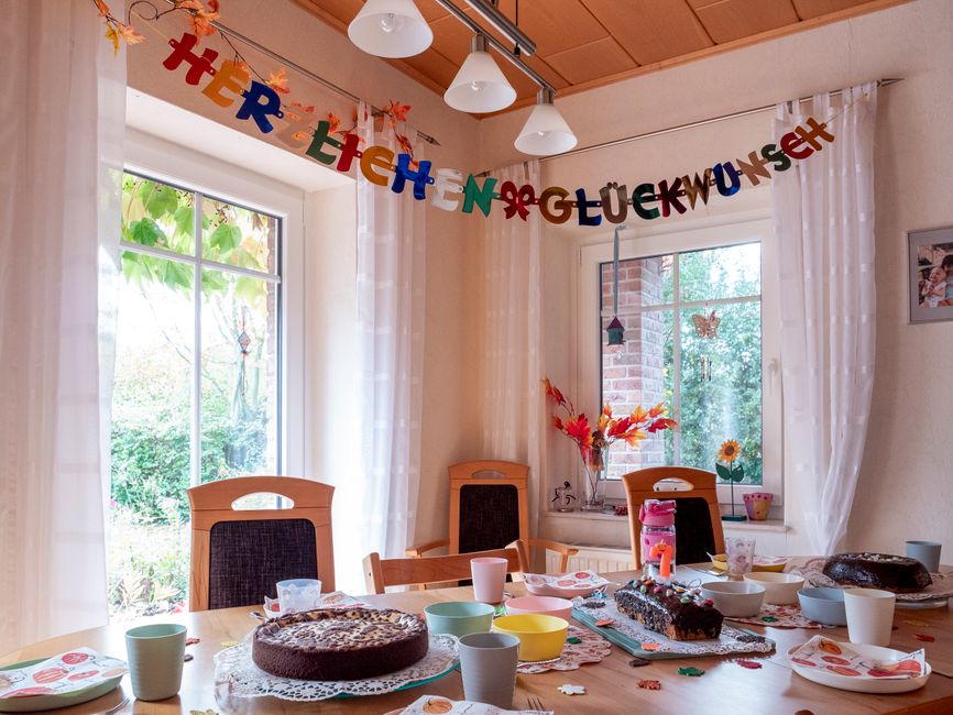 Festive indoor celebration table with cakes and colorful decorations for a joyous occasion.