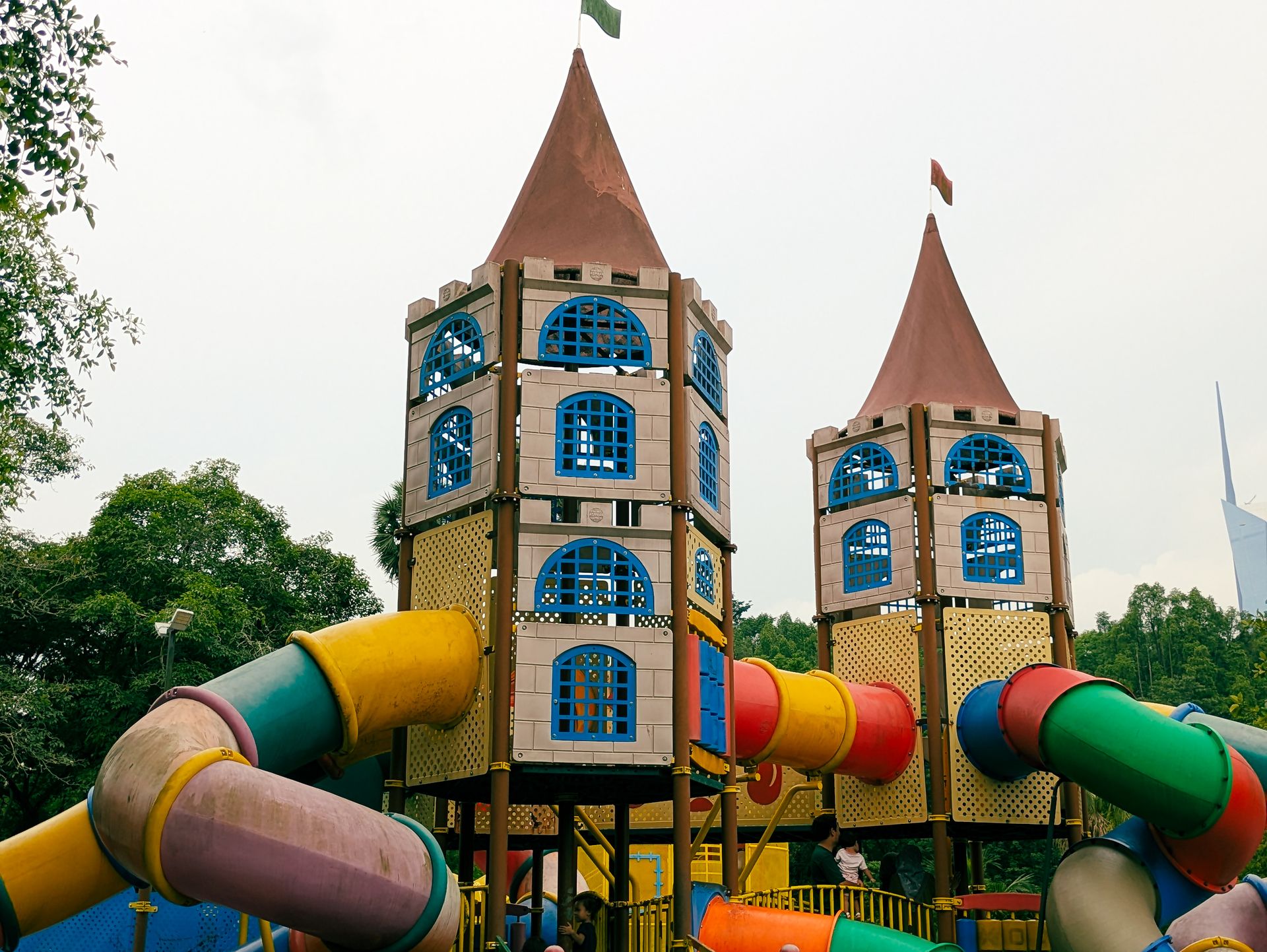 Two playful castle-like structures with vibrant slides in a park setting, perfect for family fun.
