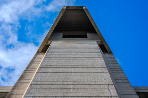Free Unique low-angle architectural shot capturing a concrete structure against a vivid blue sky with clouds. Stock Photo