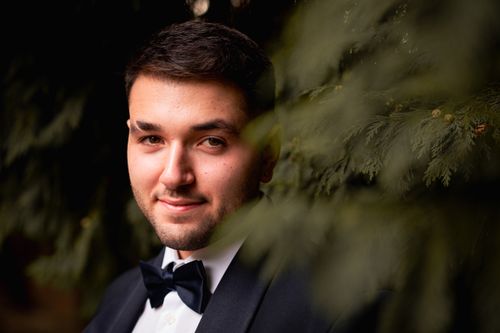 Free Close-up portrait of a well-dressed man in a tuxedo, surrounded by greenery, exuding elegance and sophistication. Stock Photo