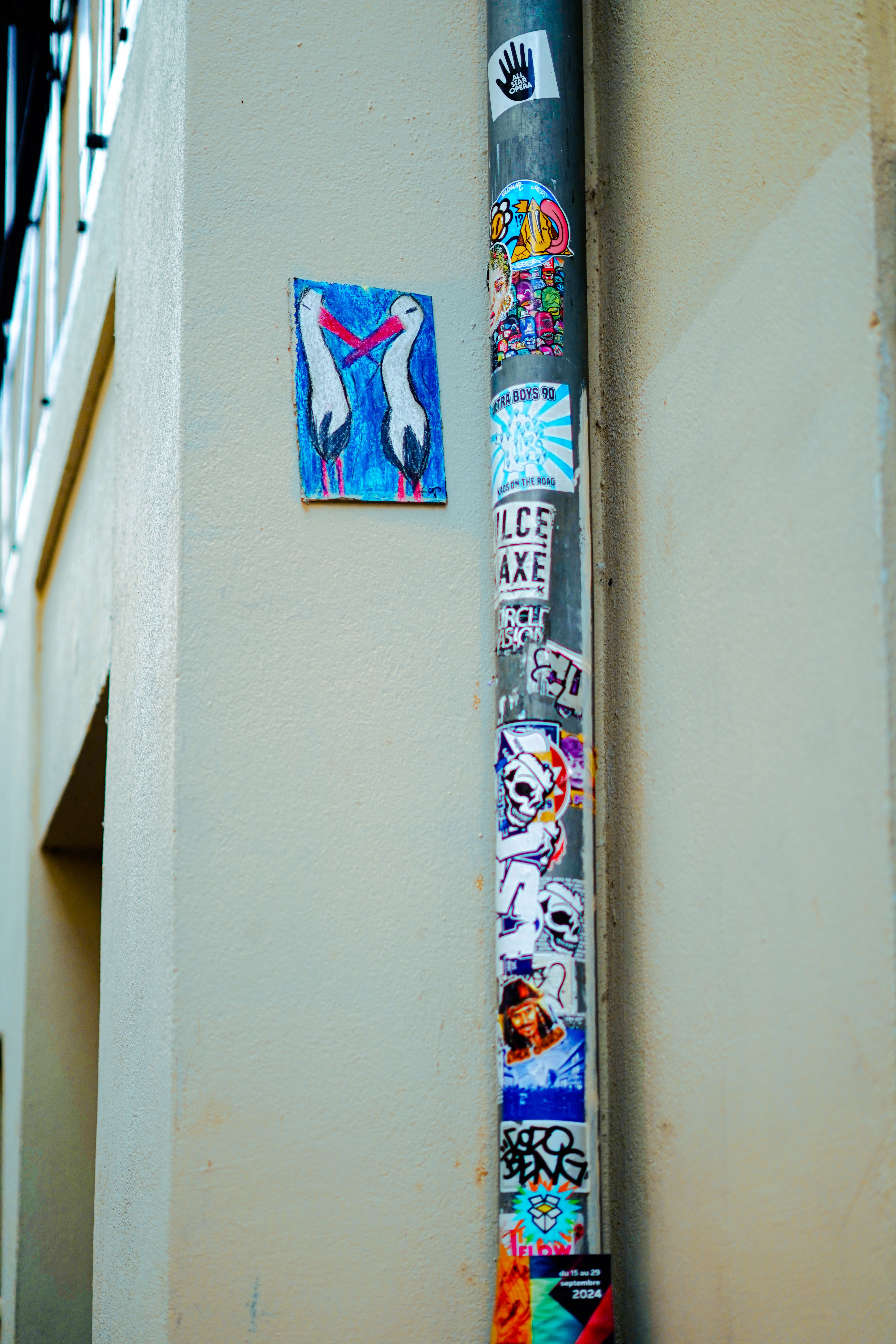 Detailed view of urban street art with stickers on a metal pole in a city environment.