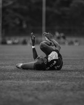 Black and white photo of a soccer player on the field in action, capturing the dynamic moment.