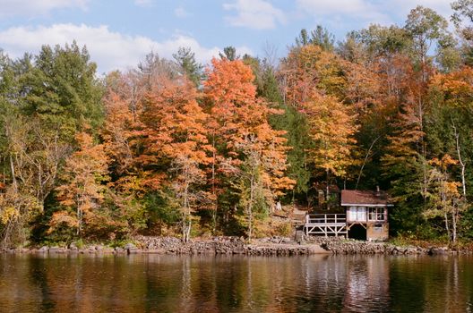 Charming lakeside cabin amidst colorful fall foliage, serene and inviting.