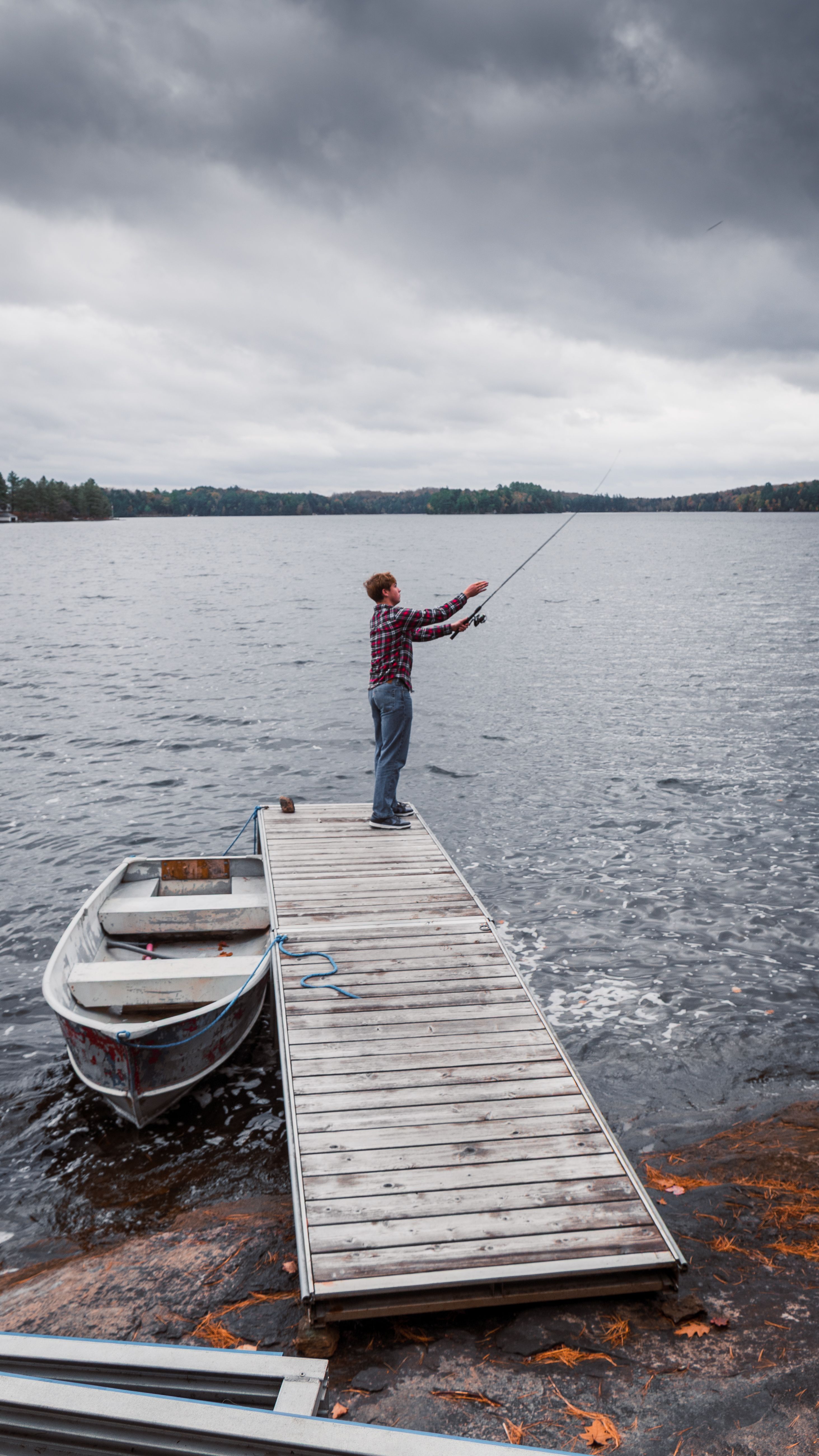 A man fishing from a dock on a peaceful lake in Ontario, Canada.