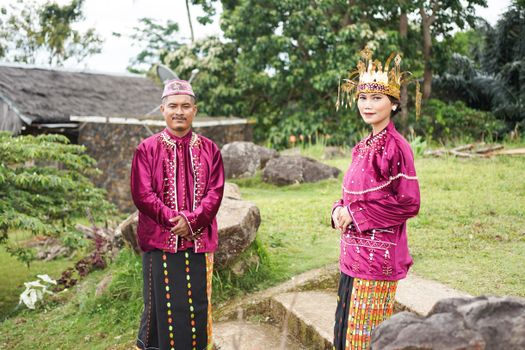 Man and woman in traditional East Nusa Tenggara attire outdoors, vibrant cultural heritage.