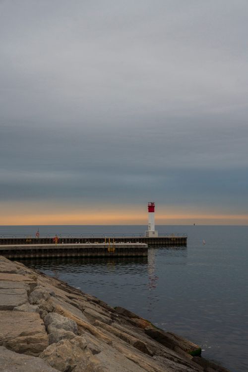Free Peaceful lighthouse view with a sunset backdrop over calm waters. Stock Photo
