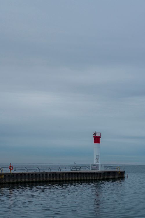 Free Peaceful view of a solitary lighthouse by the sea on a cloudy day. Stock Photo