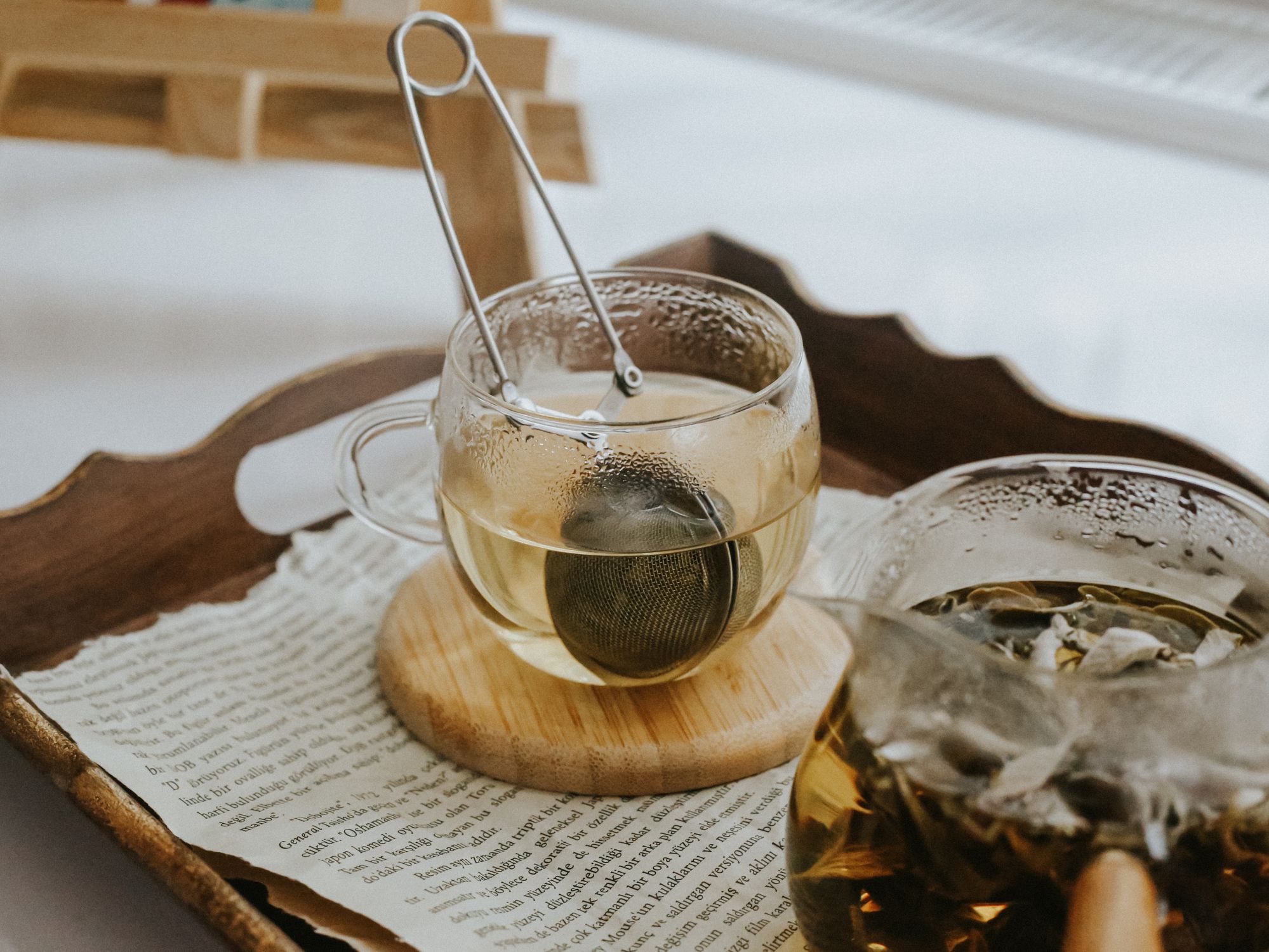 Cenas acolhedoras com xícaras de chá de vidro, infusor e papéis espalhados, simbolizando relaxamento e bem-estar.