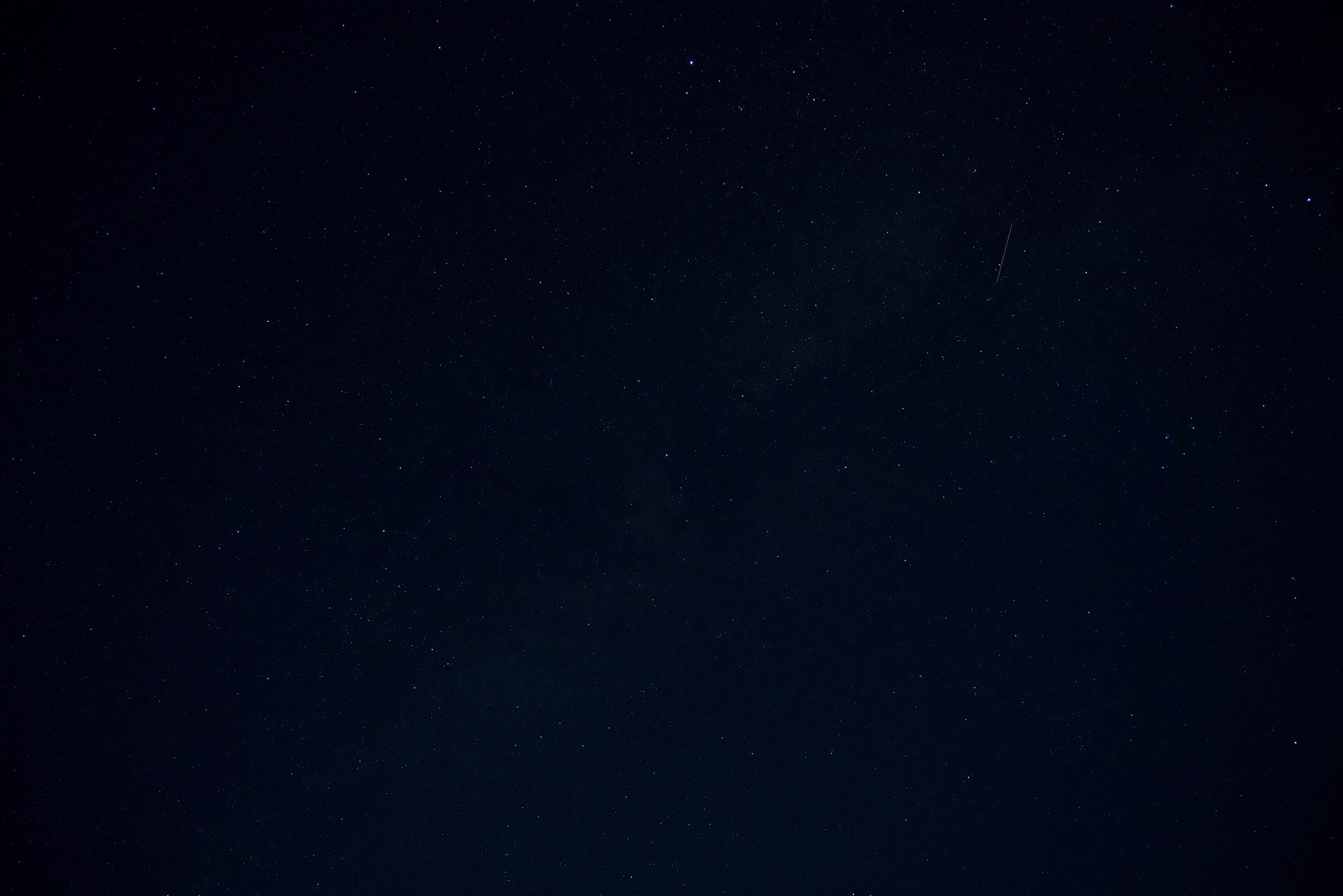 Free A tranquil starry night sky with a visible shooting star and scattered stars. Stock Photo