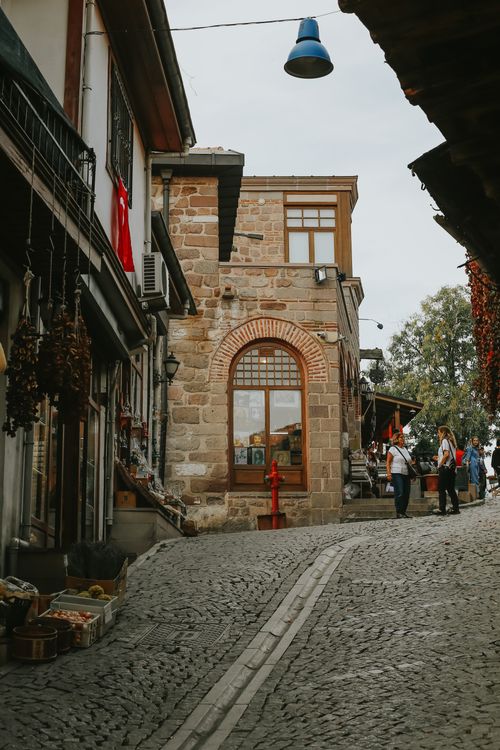Free Picturesque cobblestone street lined with historic buildings and local shops in a quaint town setting. Stock Photo