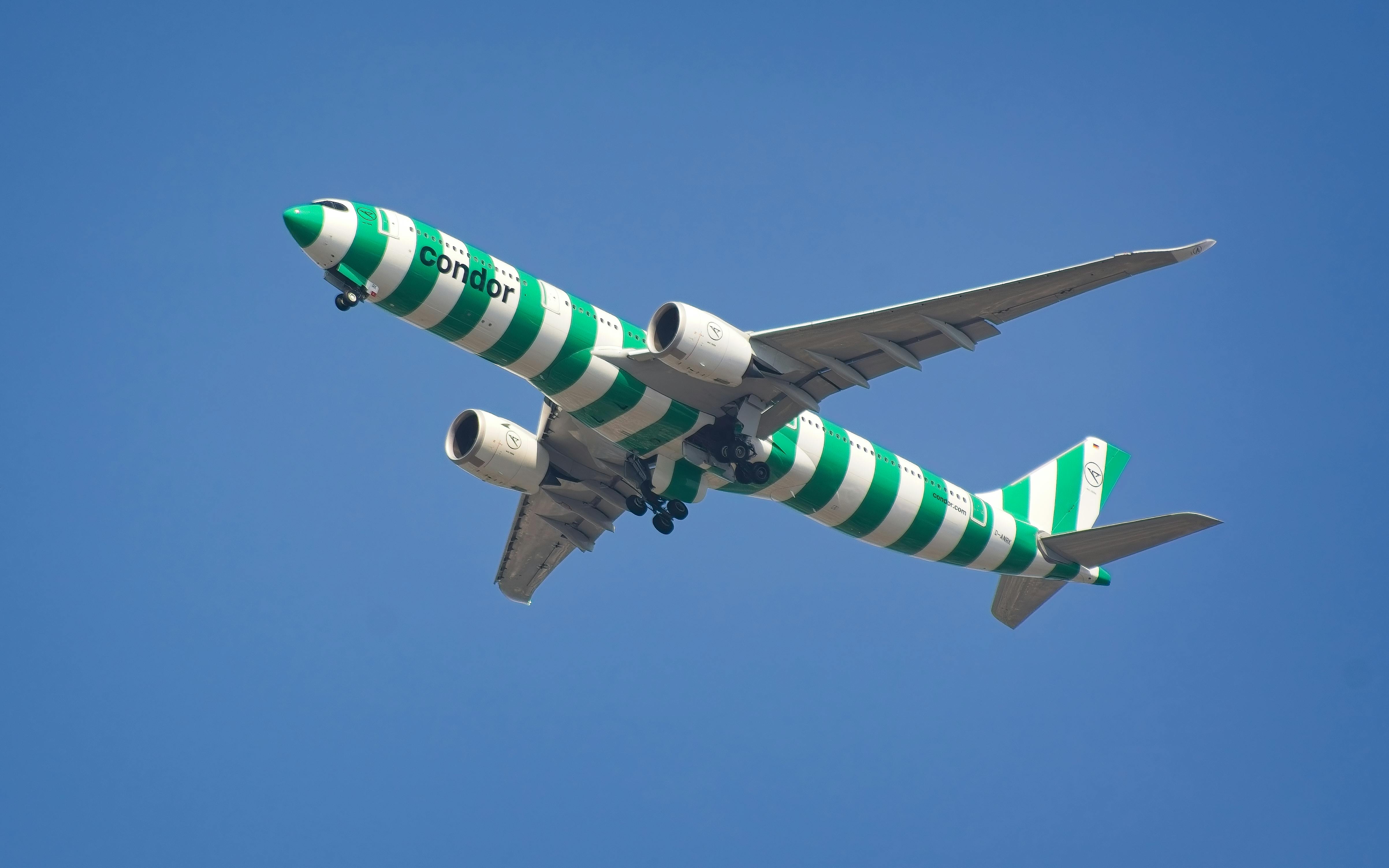 Condor Airbus A330 aircraft in green stripes landing in New York City, clear blue skies.