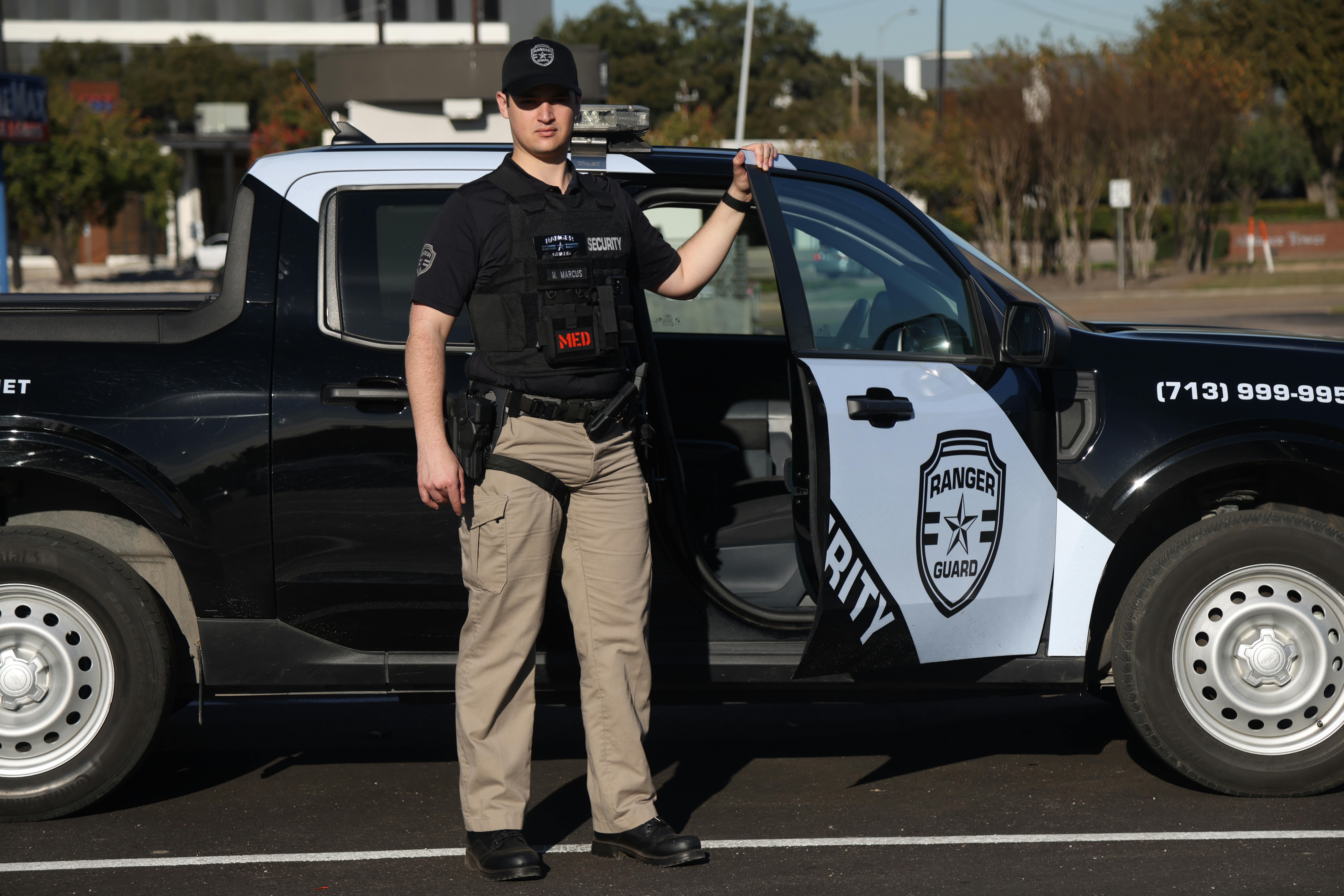 Security officer in uniform standing beside patrol vehicle in League City, Texas.