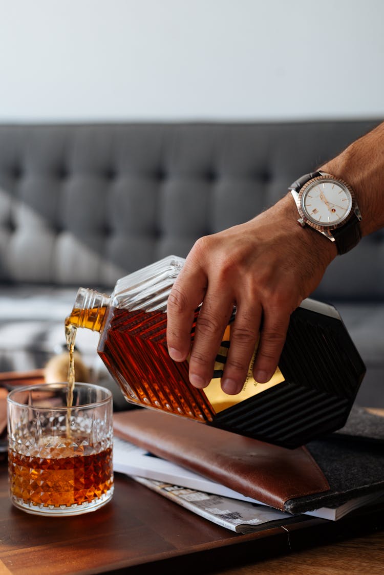 Person Pouring Liquor On Drinking Glass