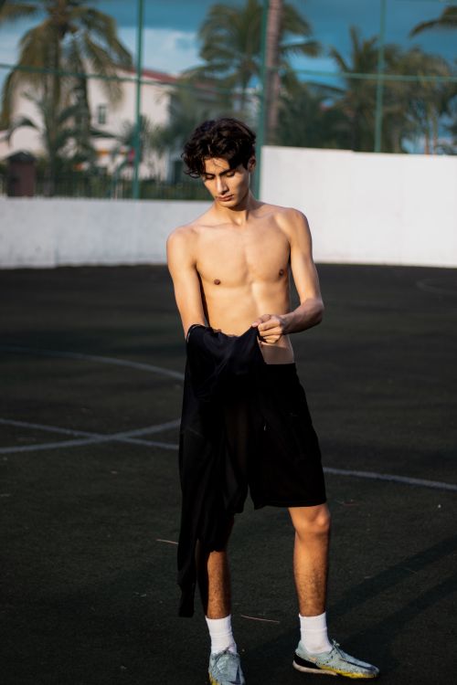 Free Young man in athletic wear on an outdoor basketball court at dusk. Stock Photo