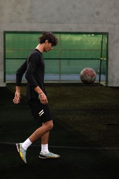 Athletic young man practicing soccer skills on a turf field.